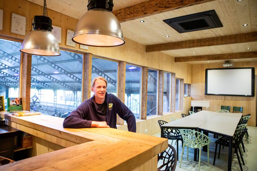 Jan Woudstra zit aan de bar van zijn ontvangstruimte en kijkt de camera in